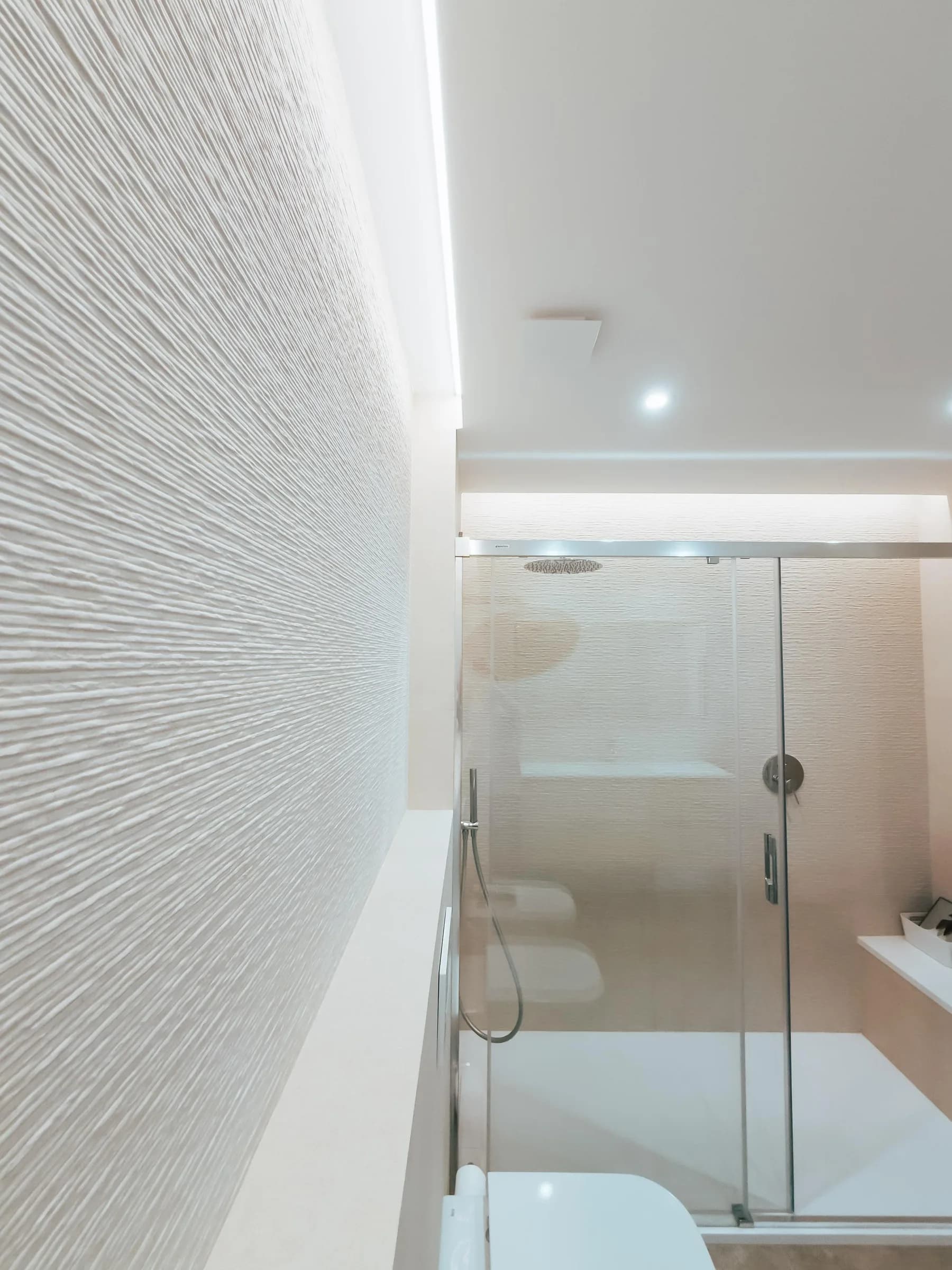 Baño reformado con ducha a ras y revestimiento texturizado de Suiteak